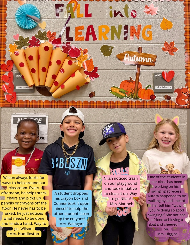 Four children smiling, standing in a row; wall behind them with decorations and a sign reading "Fall into Learning"