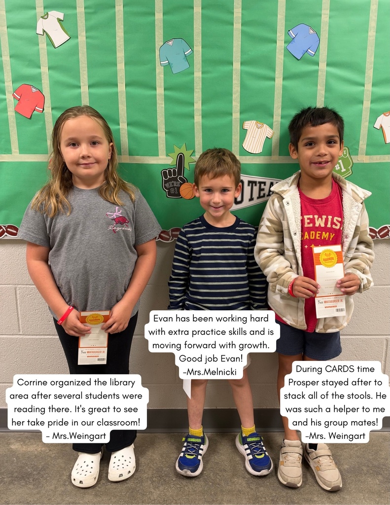Three children standing close together in front of a bulletin board. Each holds a certificate.