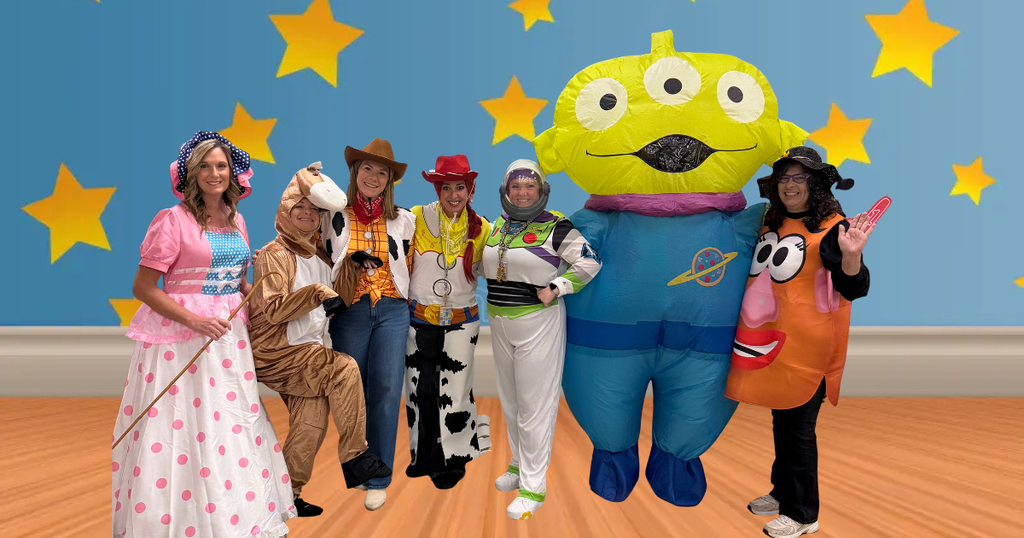 Several people in costumes standing in front of a blue wall with stars.