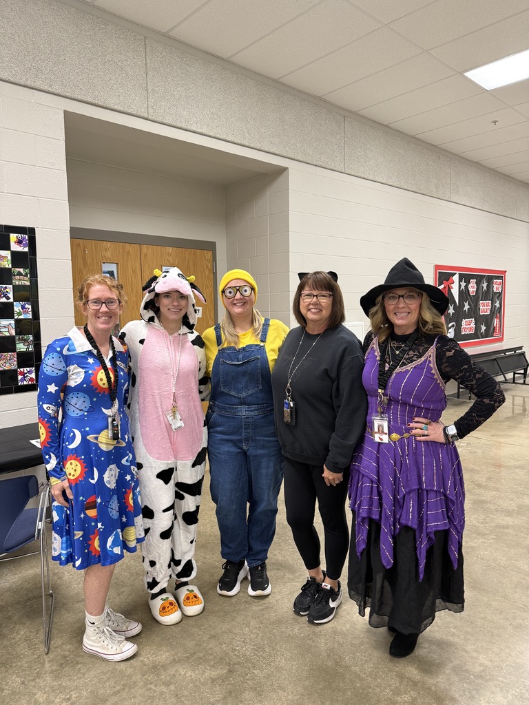 Five adults wearing costumes pose for a photo. One has cow print, one is yellow, and another is black.
