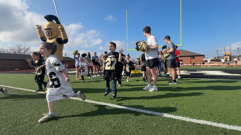 Little kids in football jerseys running with the knight