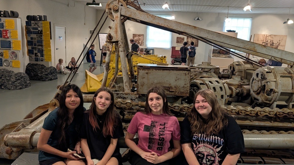 students posing in front of mining equipment