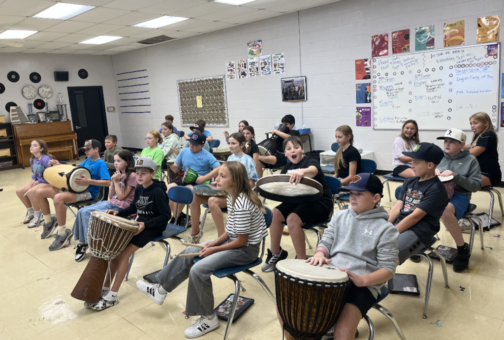 Students in a music classroom playing drums.
