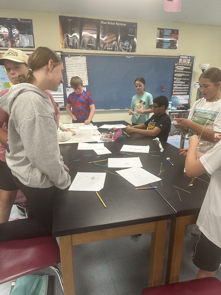 Students engaged in an engineering design challenge, building tall towers out of spaghetti and marshmallows while working in small teams.