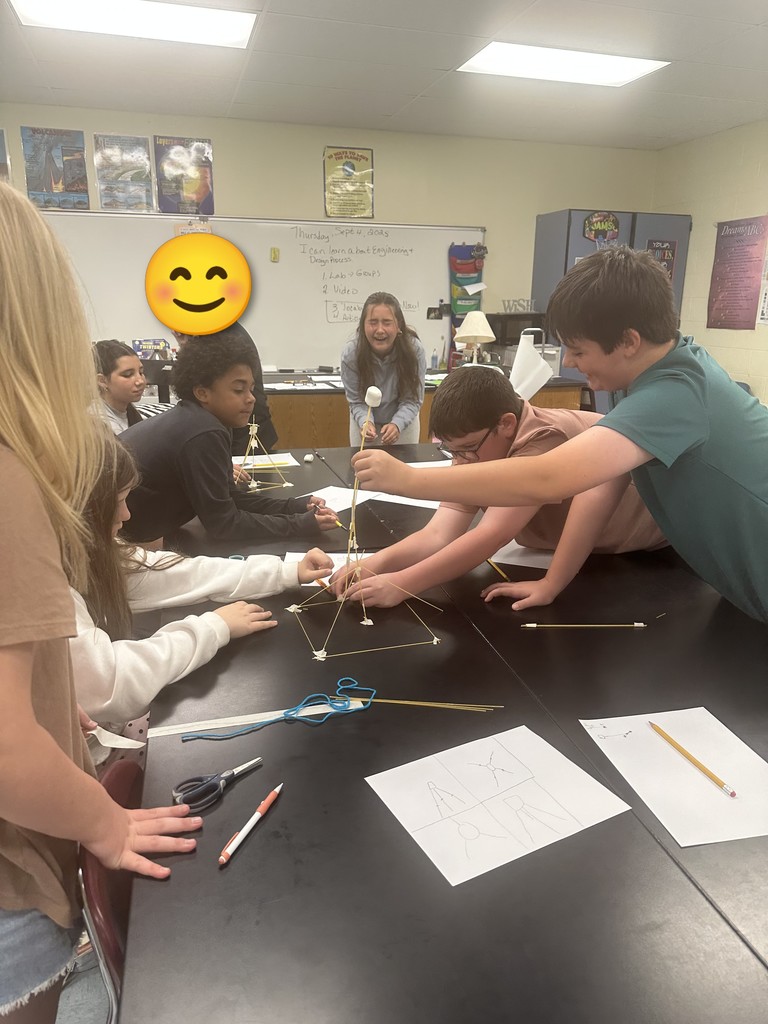 Students engaged in an engineering design challenge, building tall towers out of spaghetti and marshmallows while working in small teams.