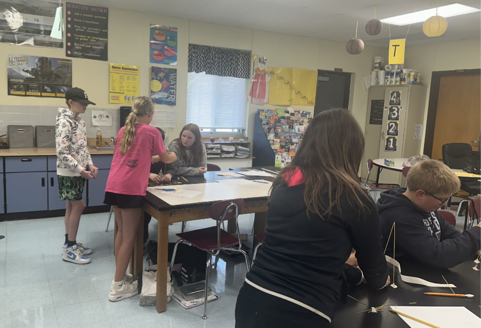 Students engaged in an engineering design challenge, building tall towers out of spaghetti and marshmallows while working in small teams.
