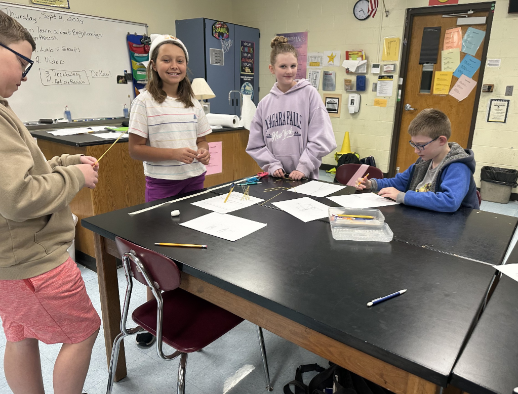 Students engaged in an engineering design challenge, building tall towers out of spaghetti and marshmallows while working in small teams.