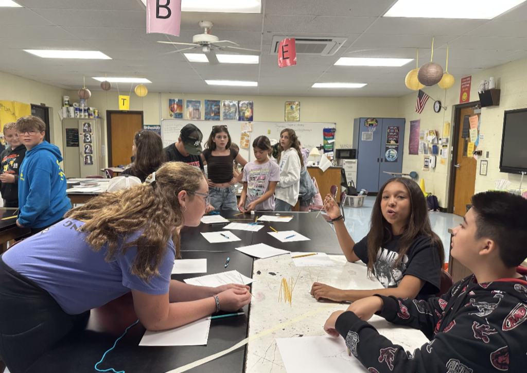Students engaged in an engineering design challenge, building tall towers out of spaghetti and marshmallows while working in small teams.