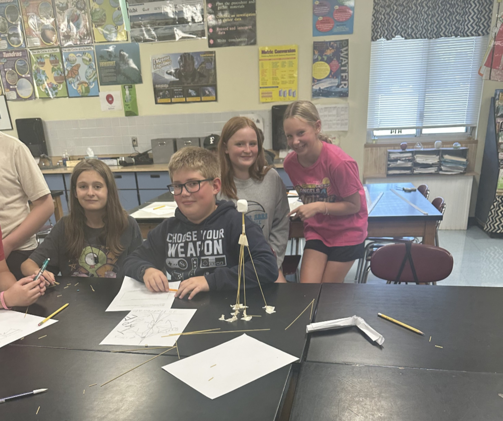 Students engaged in an engineering design challenge, building tall towers out of spaghetti and marshmallows while working in small teams.