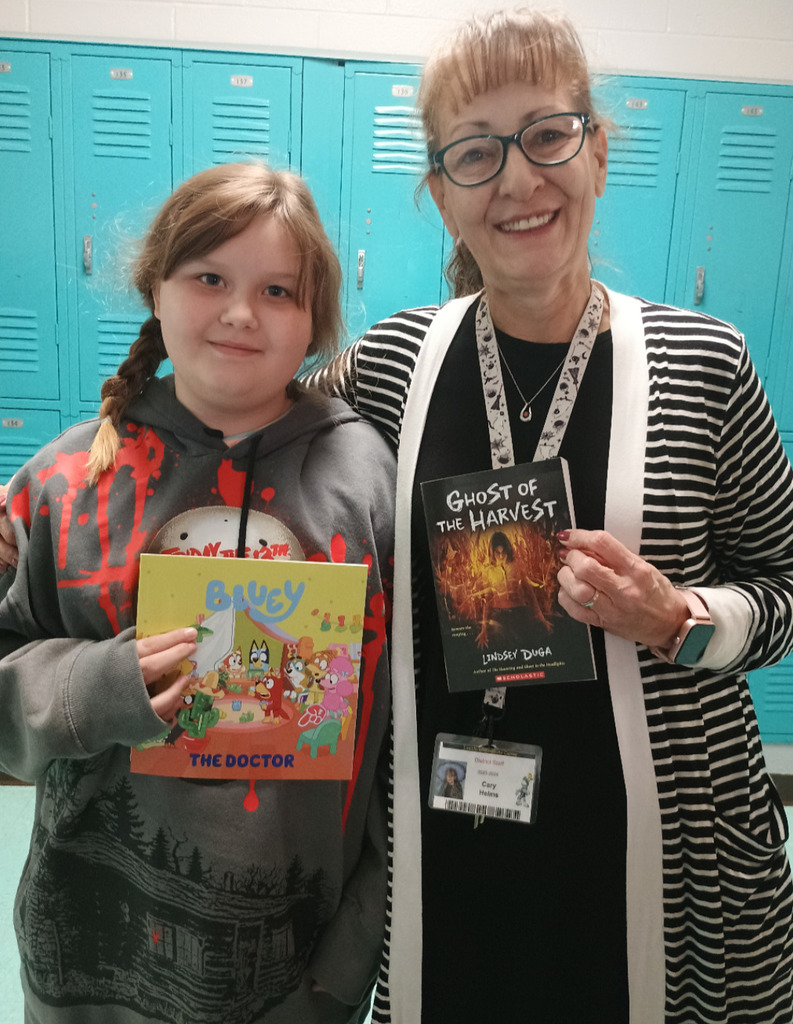 Student and teacher holding books they won from the Book Fair.