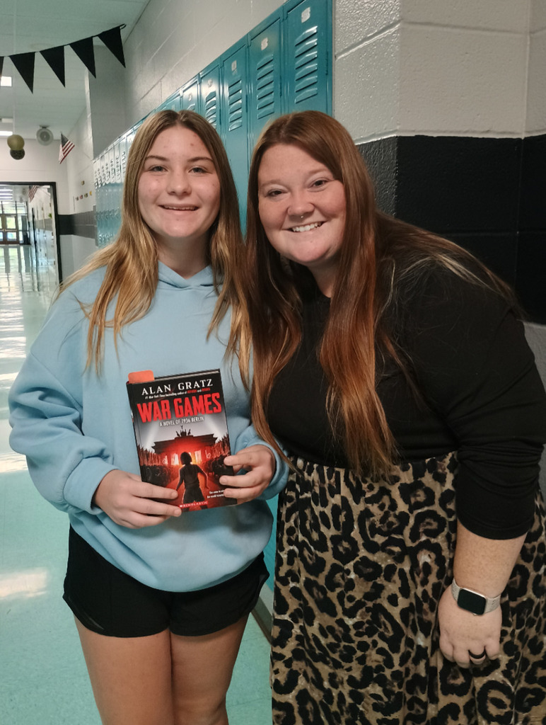 Student and teacher holding books they won from the Book Fair.