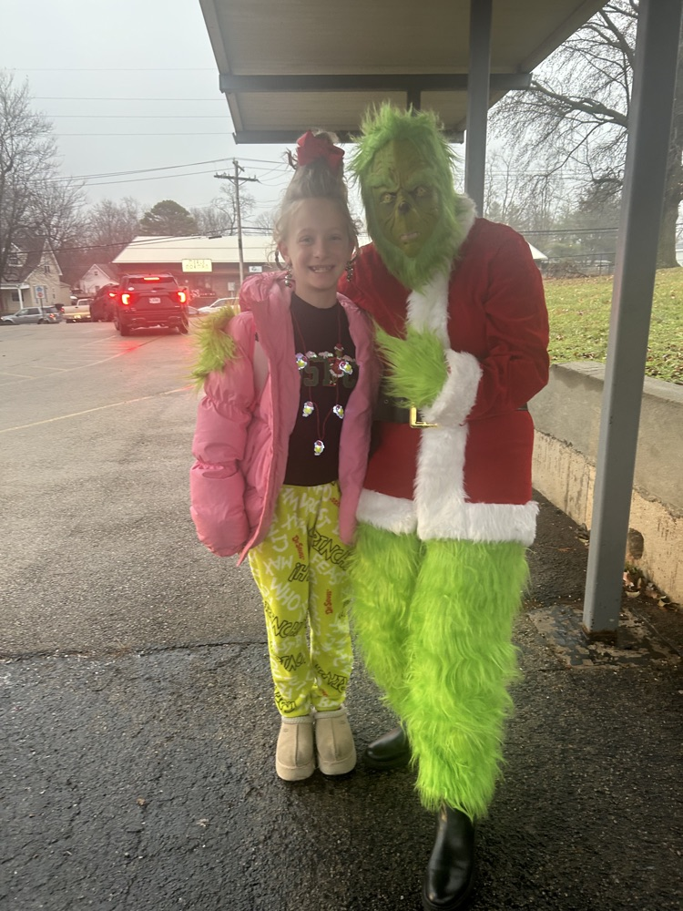 students wearing pajamas standing with the Grinch