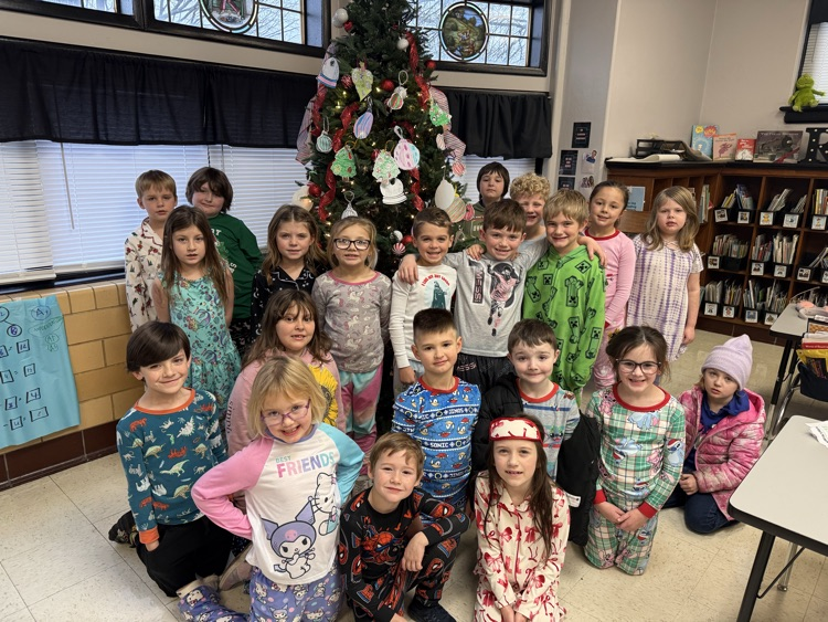 students wearing pajamas posing in front of a Christmas tree