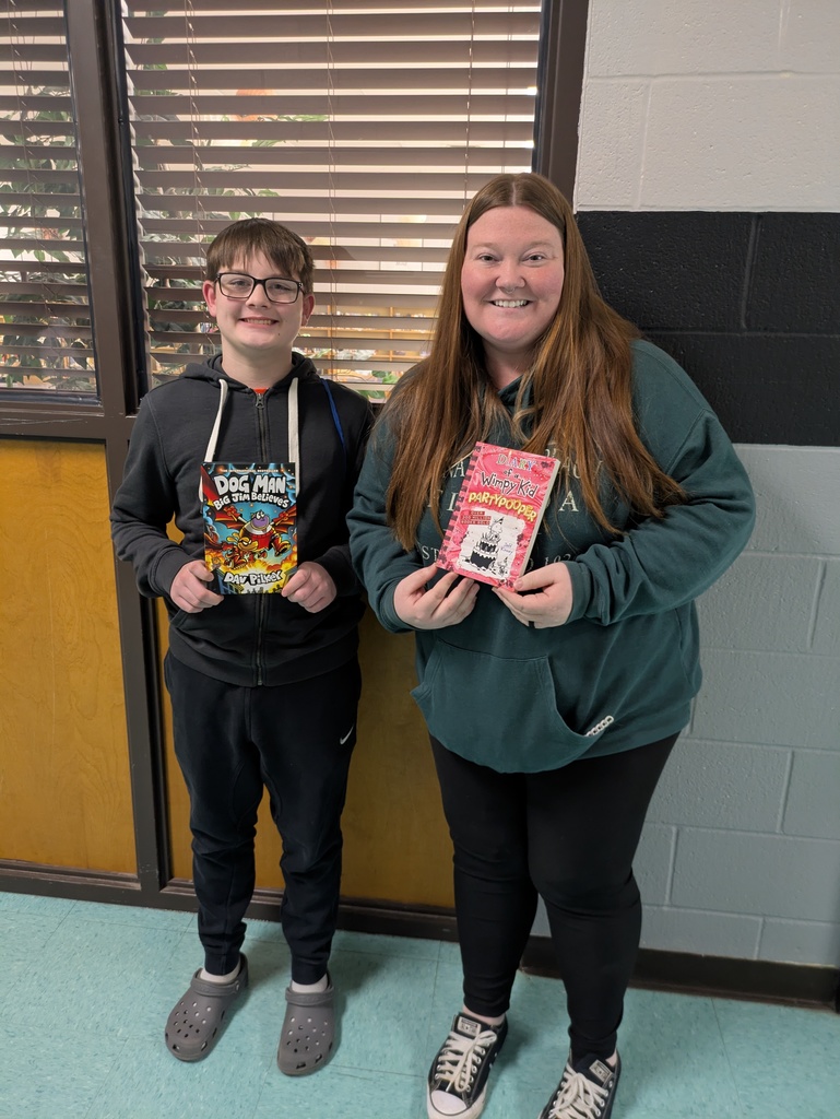 Teacher and student smiling and holding new books.