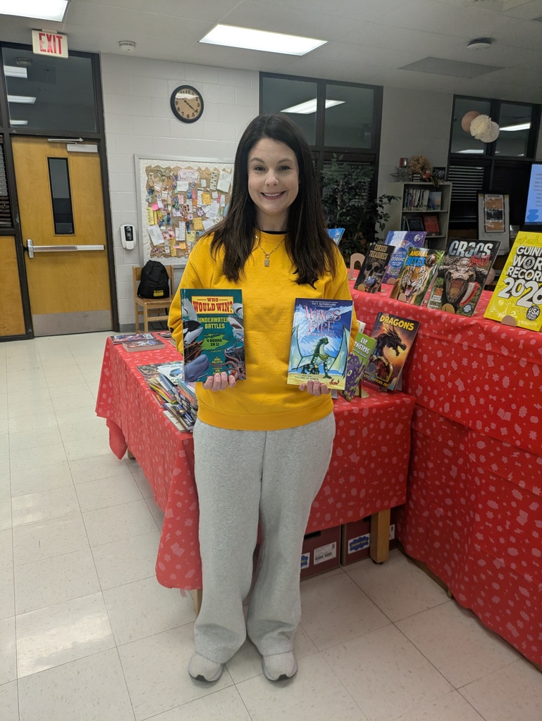 Teacher smiling and holding new books.