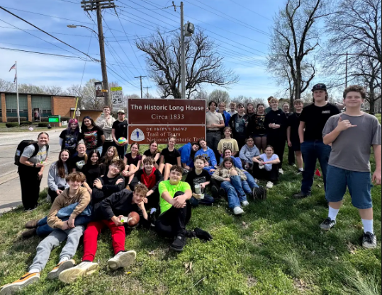 Students pose for a picture at the Long House memorial sign.