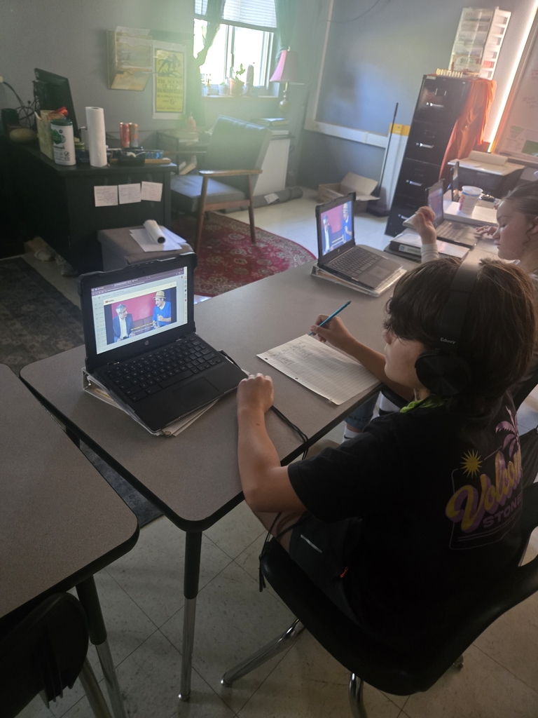 Students in a classroom sit at desks using chromebooks to participate in a virtual tour of Medieval England. One student’s screen shows a historical map, while others work together to translate Old English text.

