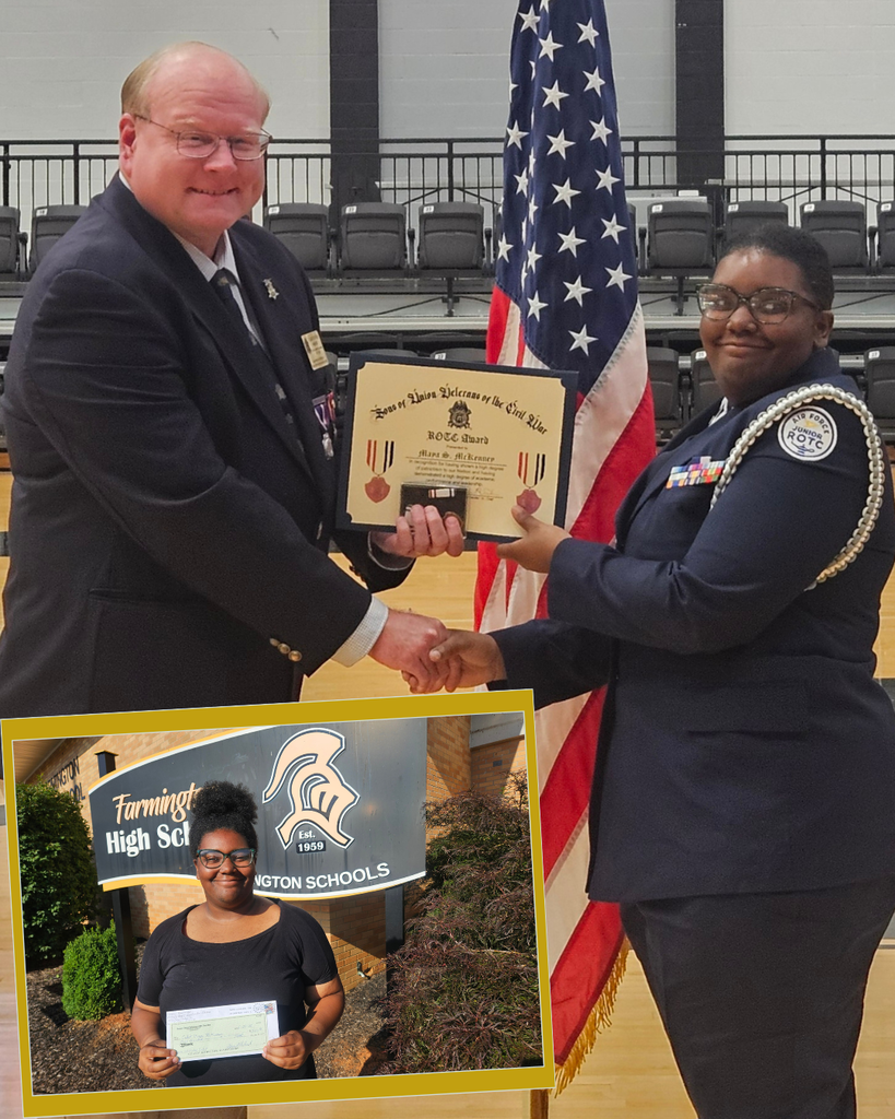 Maya McKenney shaking hands with a gentleman and holding an award. Behind them, an American flag.