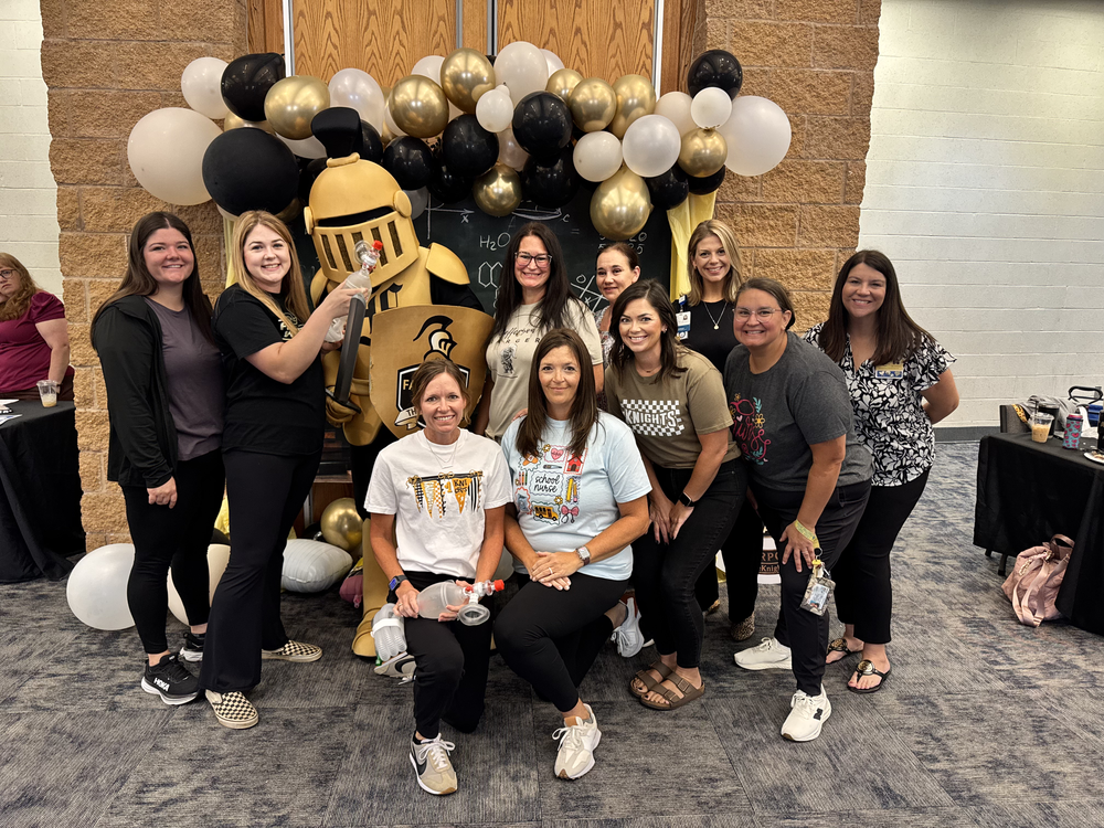 A group of people in casual attire gather for a photo in front of a balloon display.