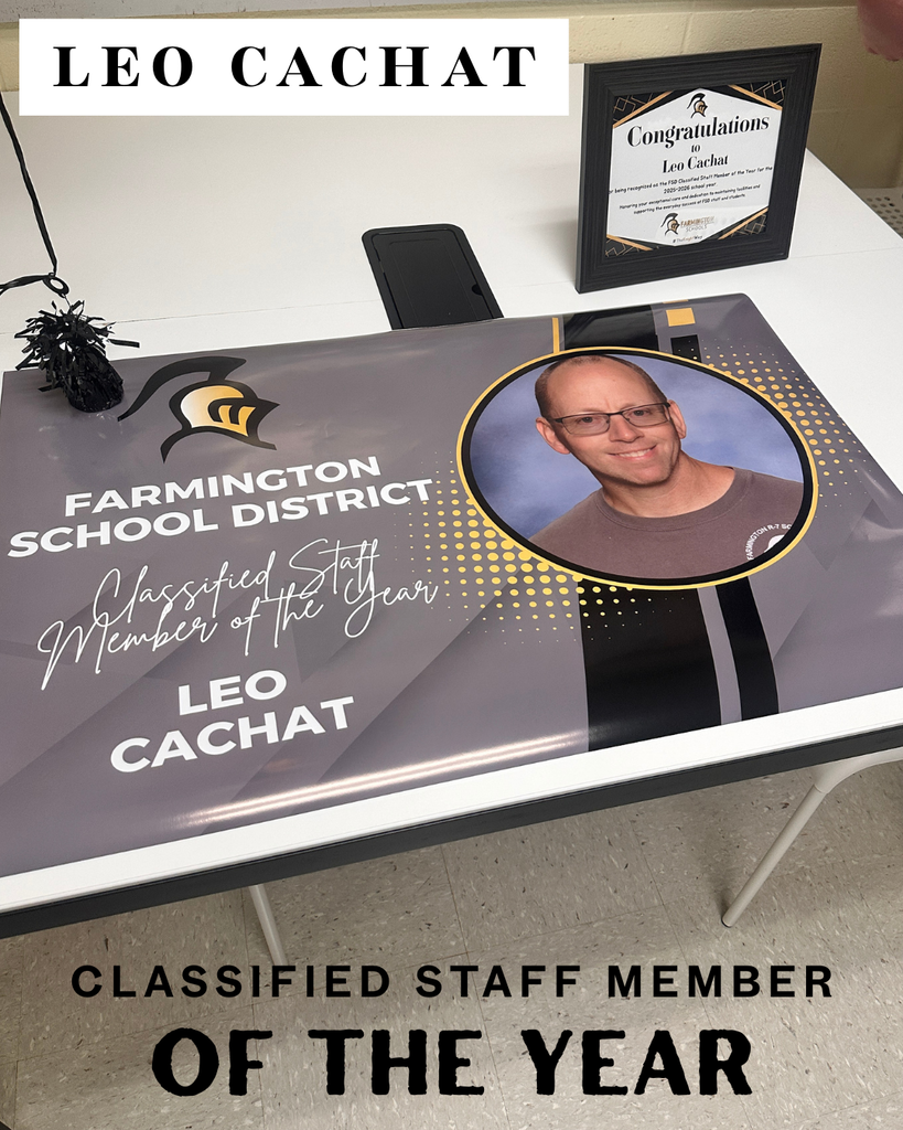 Display table with a poster reading "Classified Staff Member of the Year" and a photo of Leo Cachat.