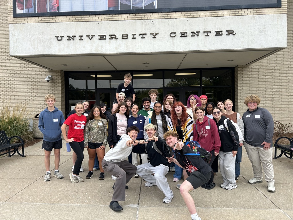 A large group of young people standing in front of a University Center building. Some are posing.