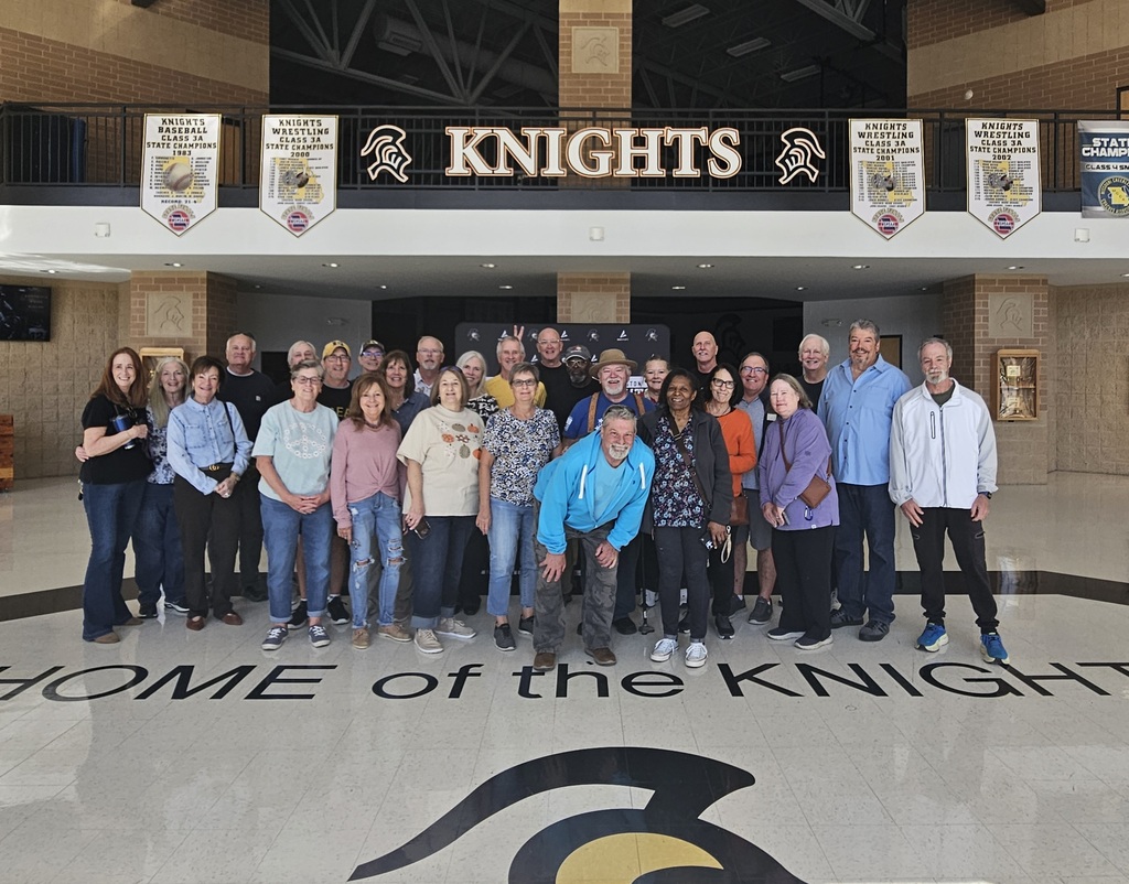 A group of people standing in front of a building with "Knights" above them.