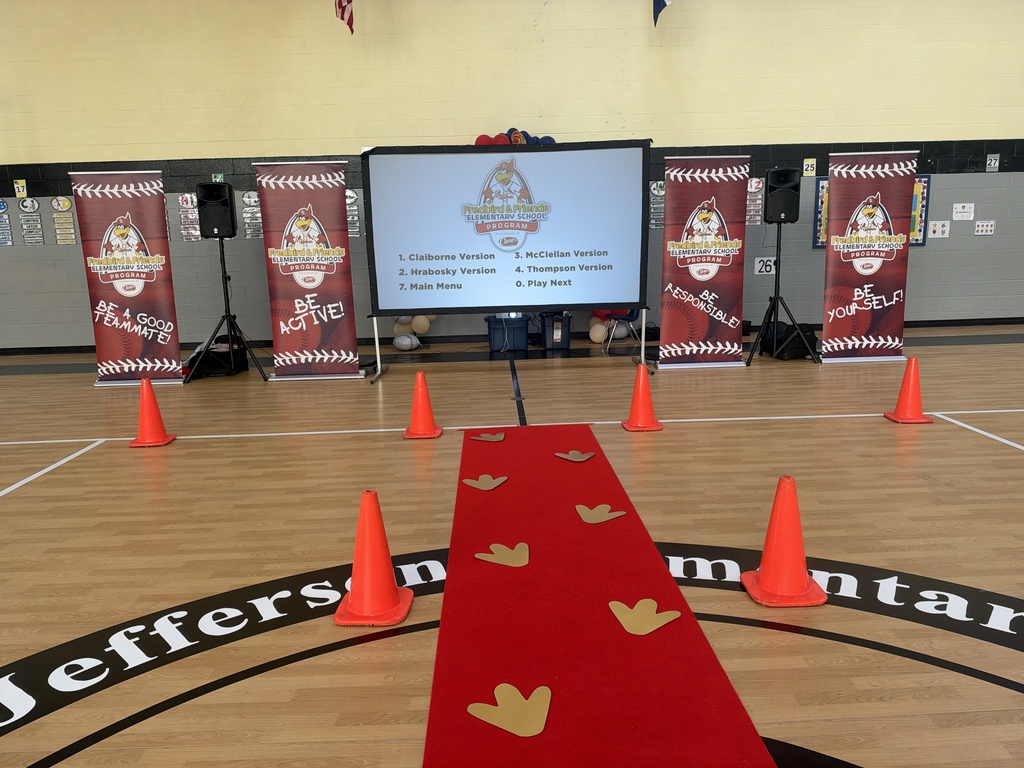 Indoor basketball court with a large screen, red carpet, and banners. Orange cones line the carpet, with the word "Jeffers" on the floor.