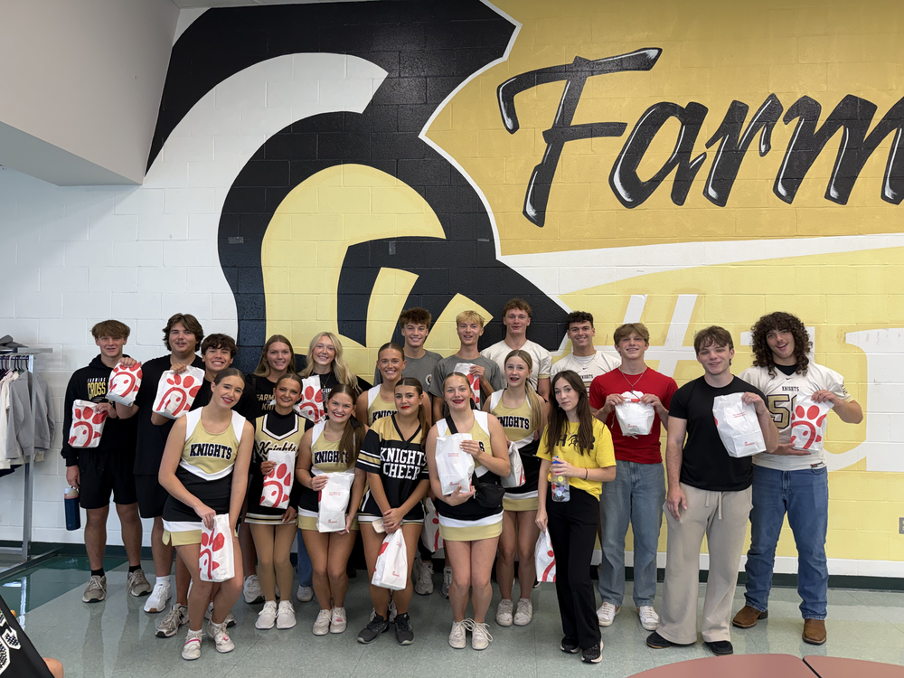 Group of students in front of a yellow and black wall that says Farm, holding white bags.