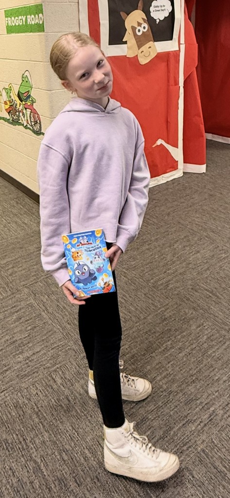 Female Kindergarten Student Holding Book that they won from the book vending machine for being a good seed 
