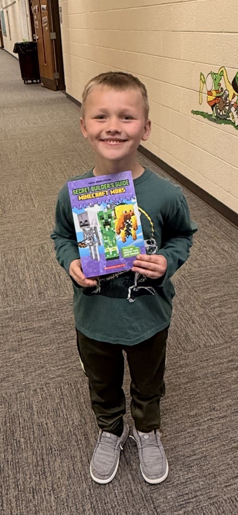 Male Kindergarten Student Holding Book that they won from the book vending machine for being a good seed 