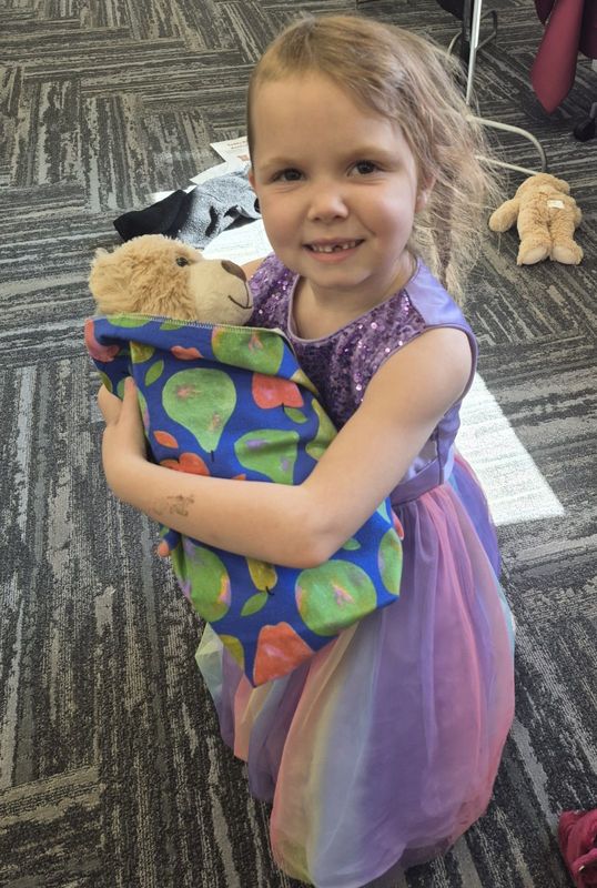 1ST GRADE GIRL HOLDING TEDDY BEAR WRAPPED IN BLANKET 