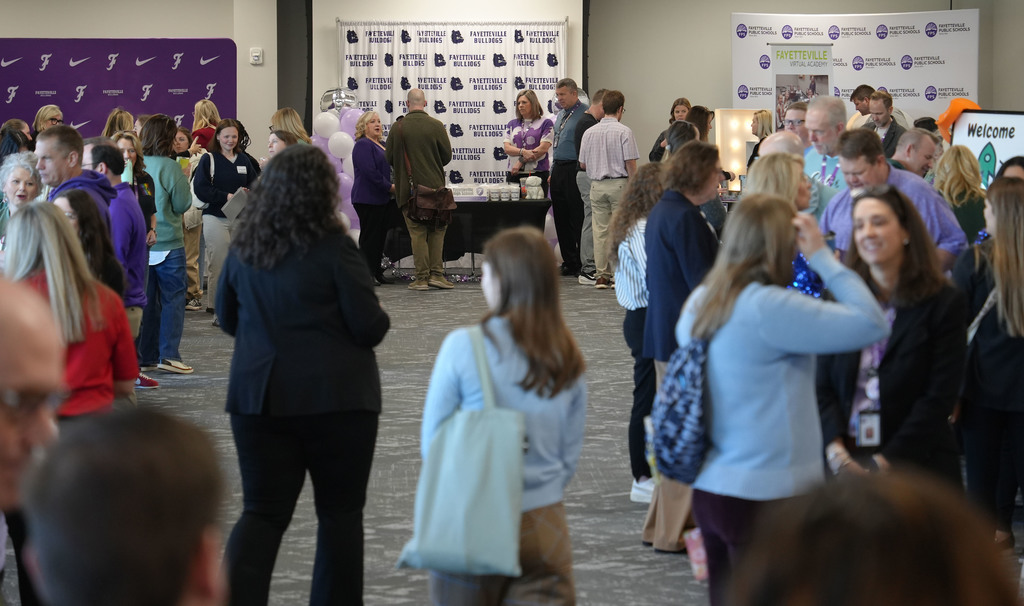 Crowd of people in a room with two banners. Some are talking to others and others are walking.