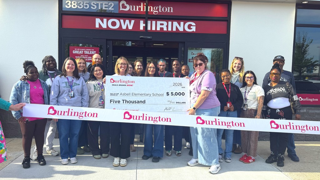 A group of people standing in front of a building with a sign that says Now Hiring.