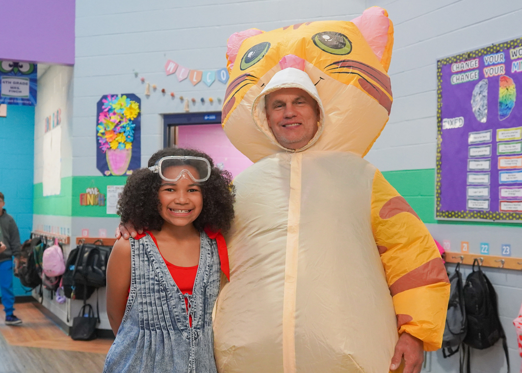 A man in a cat costume and a girl in a red top stand close to each other.