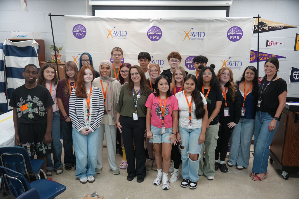 A group of individuals in casual clothing and name tags pose for a picture in a room.