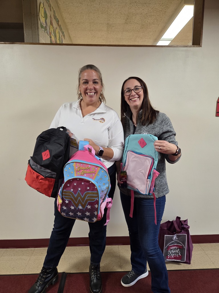 the principal and a rep from Peoples state bank hold up the donated backpacks for students