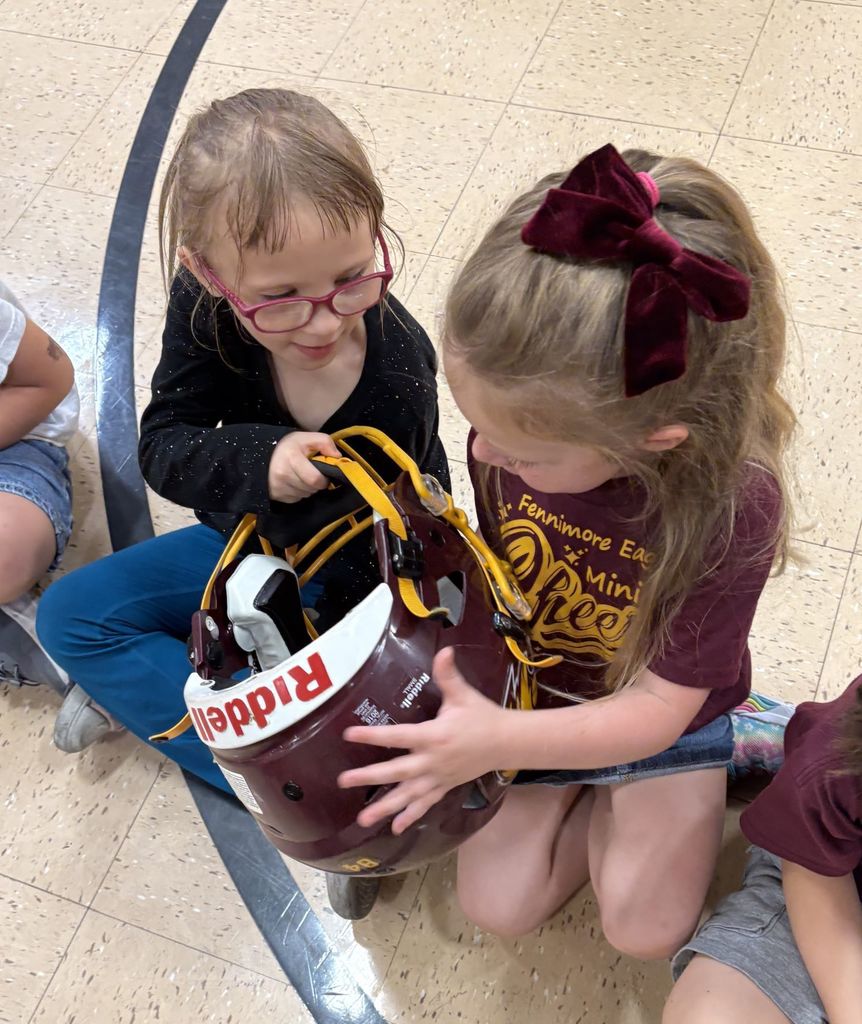student hand around a helmet when the football team visited them in the gym