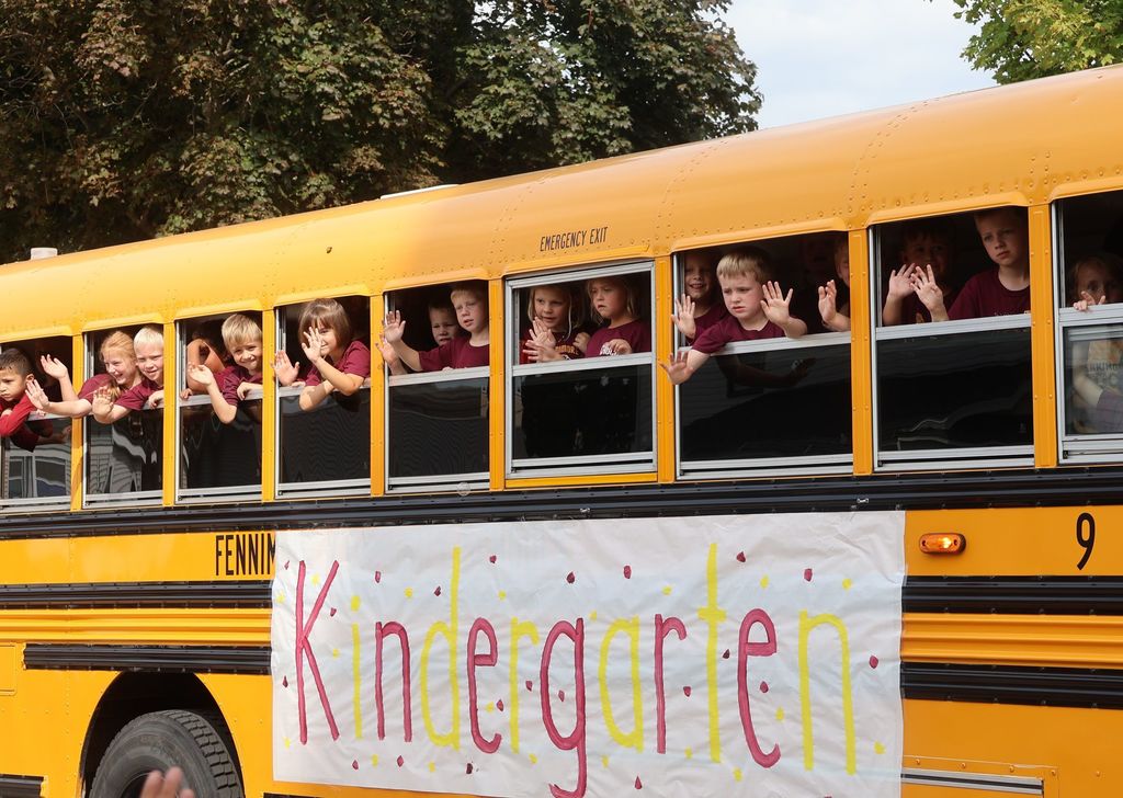 Kindergarten ride in a bus through parade and wave