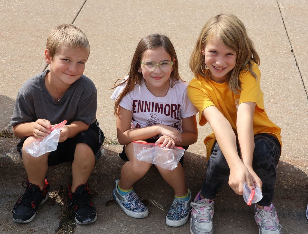 students enjoy the parade as they sit on the sidewalk
