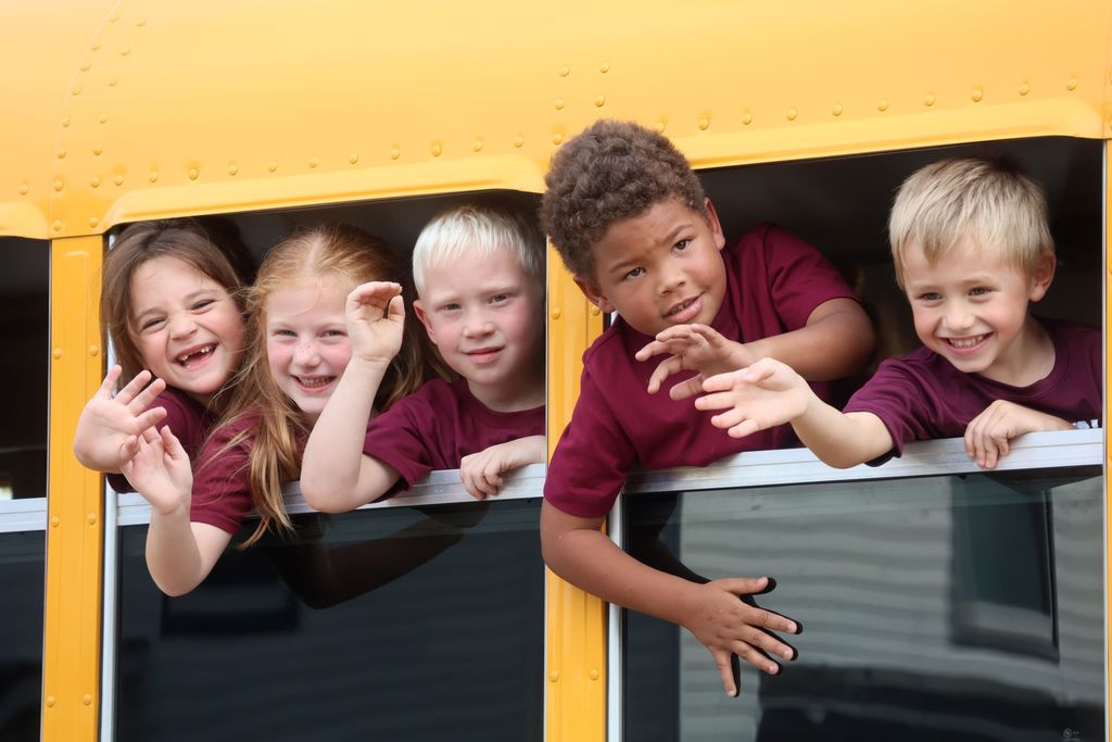 5K kids wave out the window on the bus in the parade