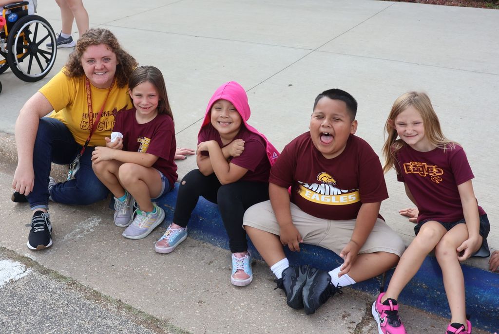 students and their teacher enjoy the parade as they sit on the sidewalk