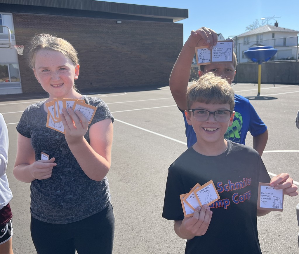 students show off the cards they collected in the predator play game outside