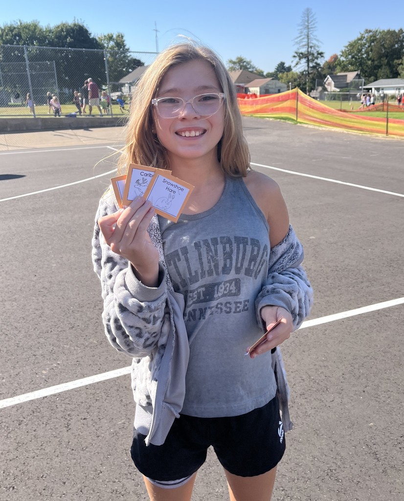 a student show off the cards they collected in the predator play game outside