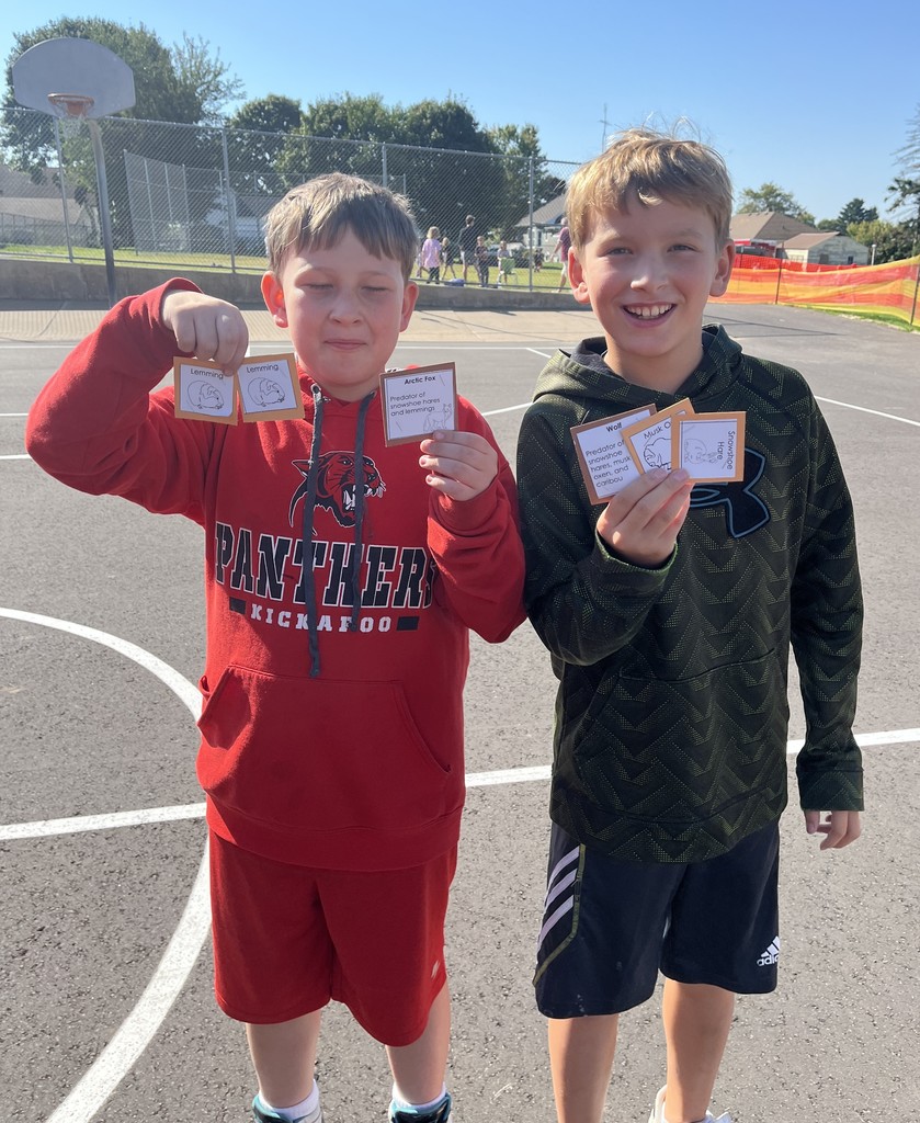 students show off the cards they collected in the predator play game outside