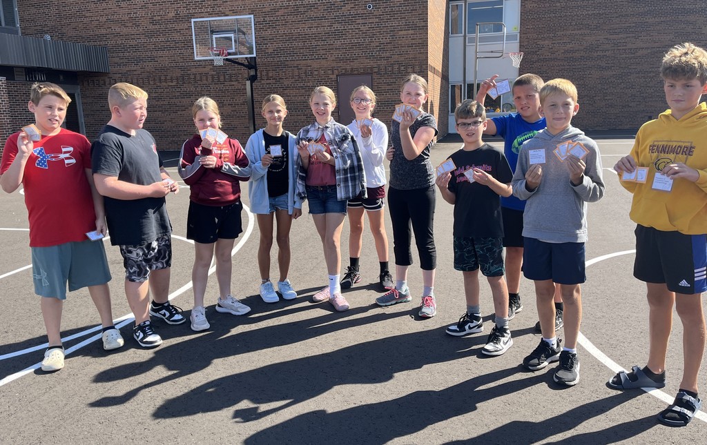 students show off the cards they collected in the predator play game outside