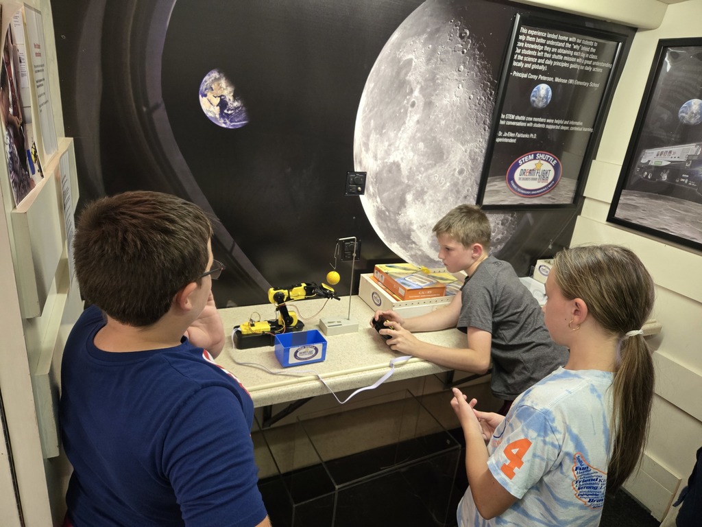 students use a robotic arm to move things on the STEM shuttle bus