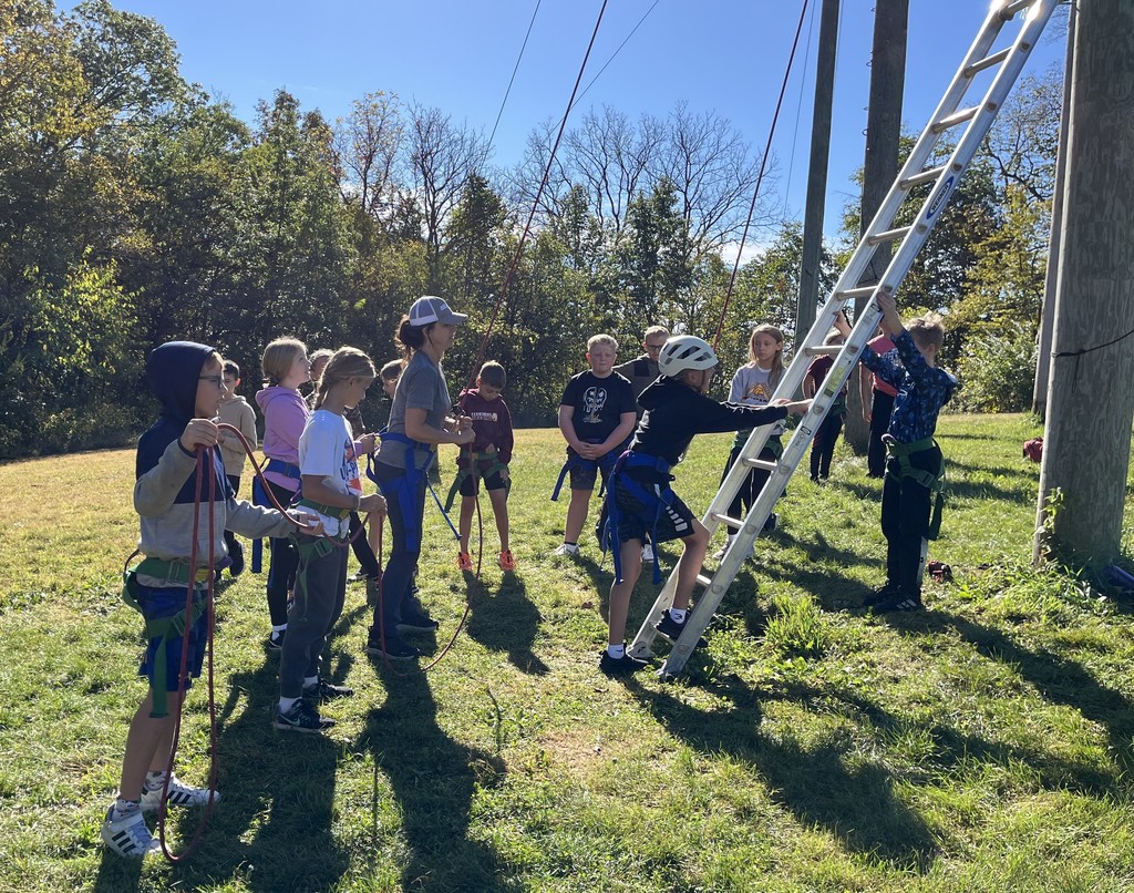 students listen to directions for an outdoor activity at Bethel Horizons and one students start to climb the ladder