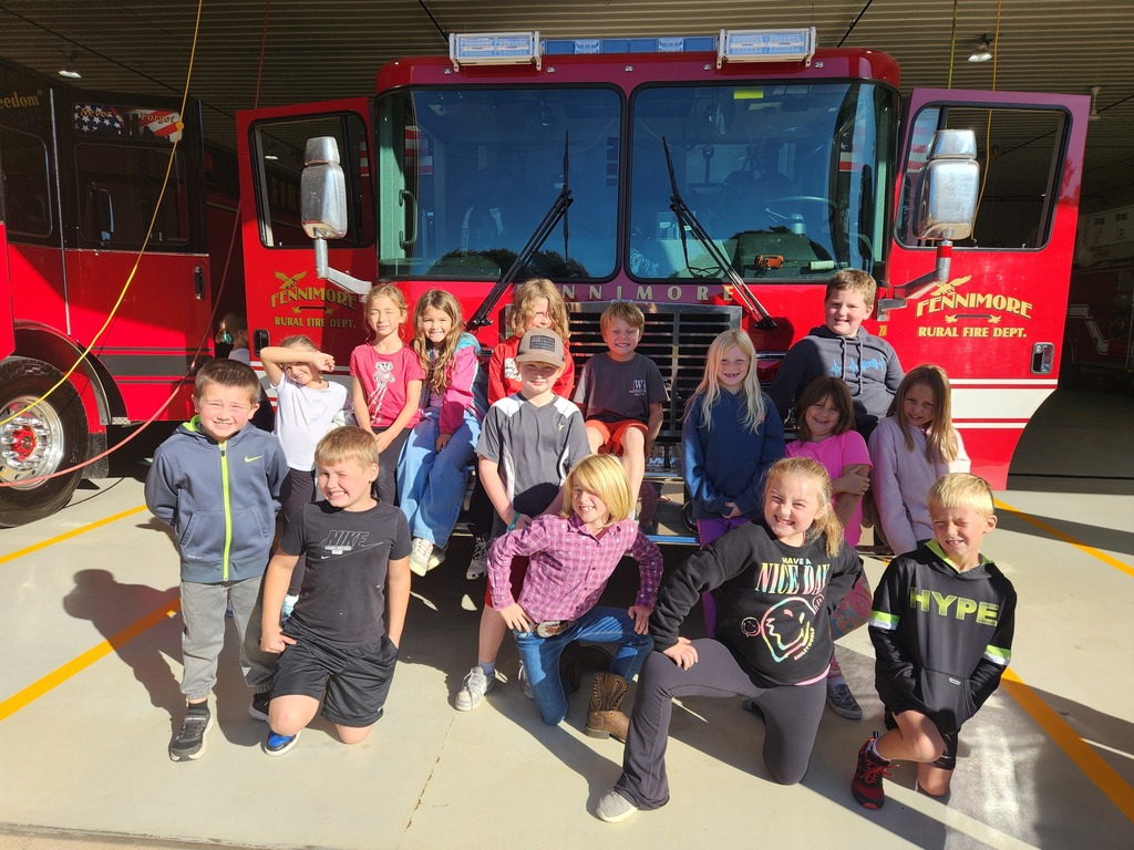 students pose for a picture in front of a fire truck at fennimore fire station.