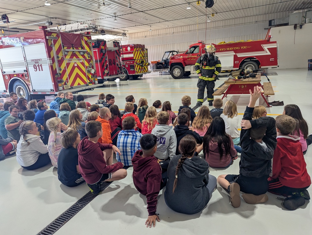 students listen to a firefighter explain the different part of his fire suit