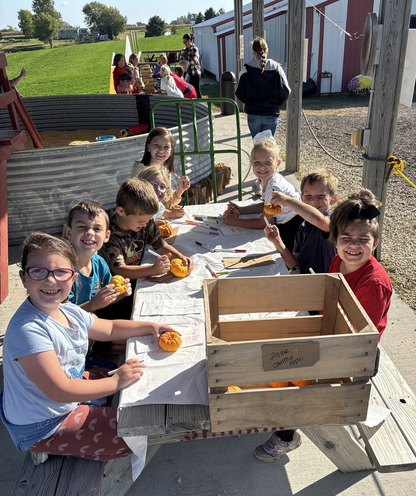 students decorate their small pumpkins at the orchard